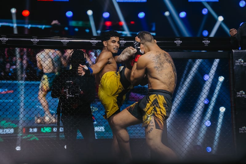Corner acompanhando o combate rente à grade do cage da LMC